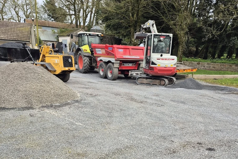 A digger and a roller preparing a driveway for a tar and chip paving