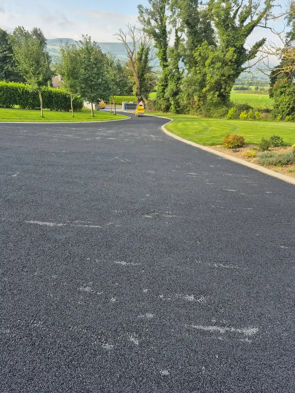 a worker rolling tar and chip onto a driveway