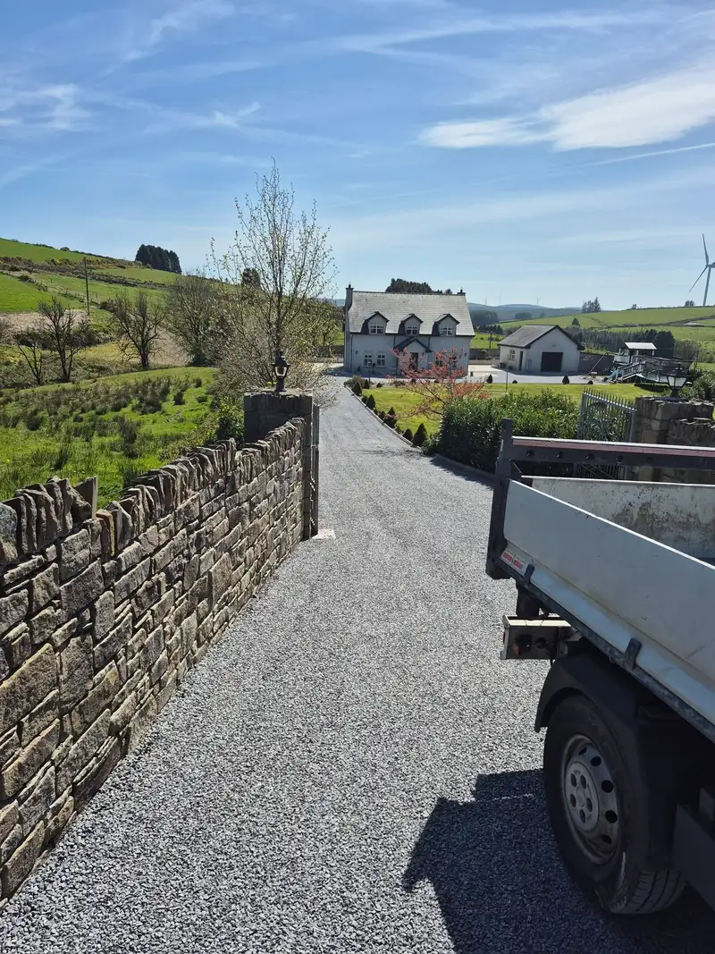 a flatbed truck parked on a tar and chip driveway