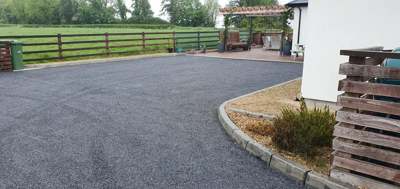 dark coloured tar and chip driveway at the side of a house