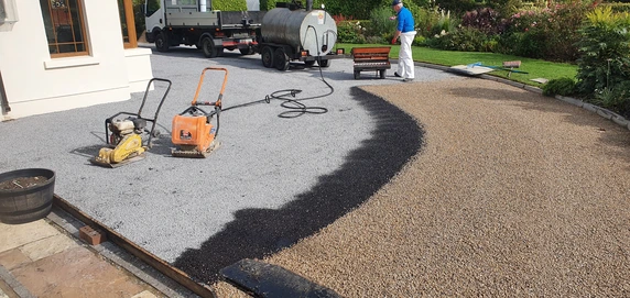 image of a driveway next to a house being tarred and chipped